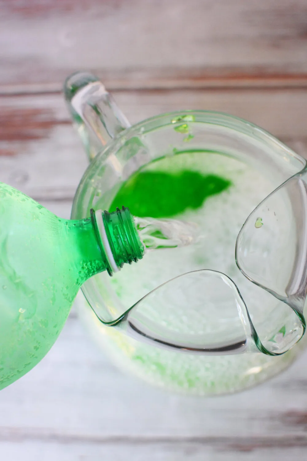 Pouring lime soda into a pitcher with jello. 