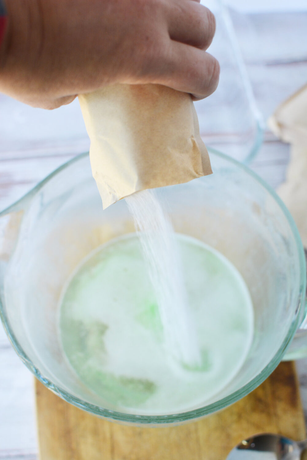 Pouring a packet of lime gelatin into a bowl. 