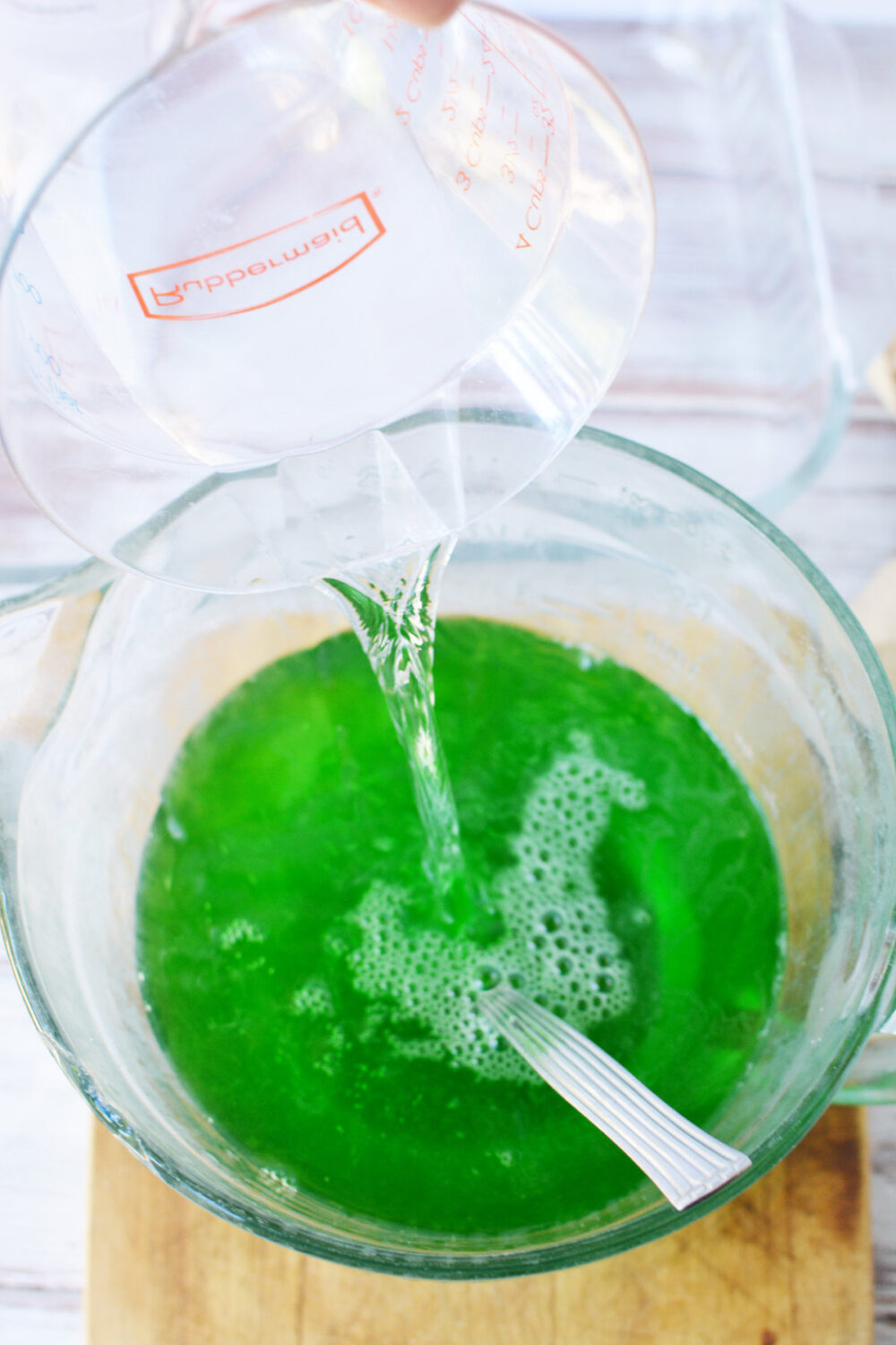 Pouring water into green jello mixture. 