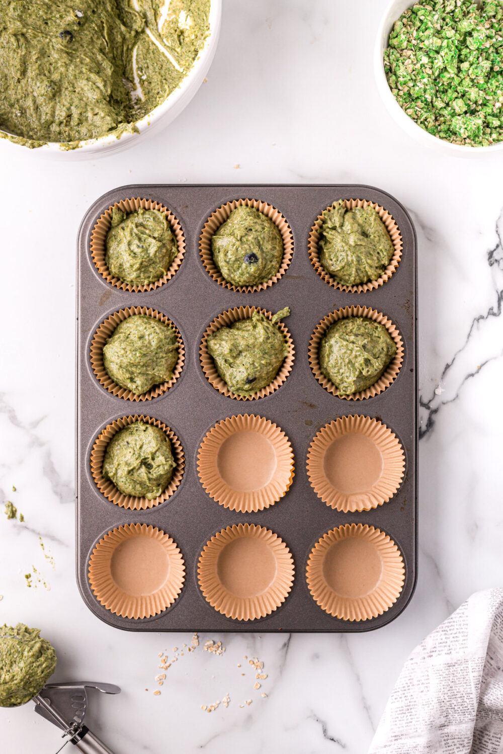 Filling muffin cups with spinach banana batter. 