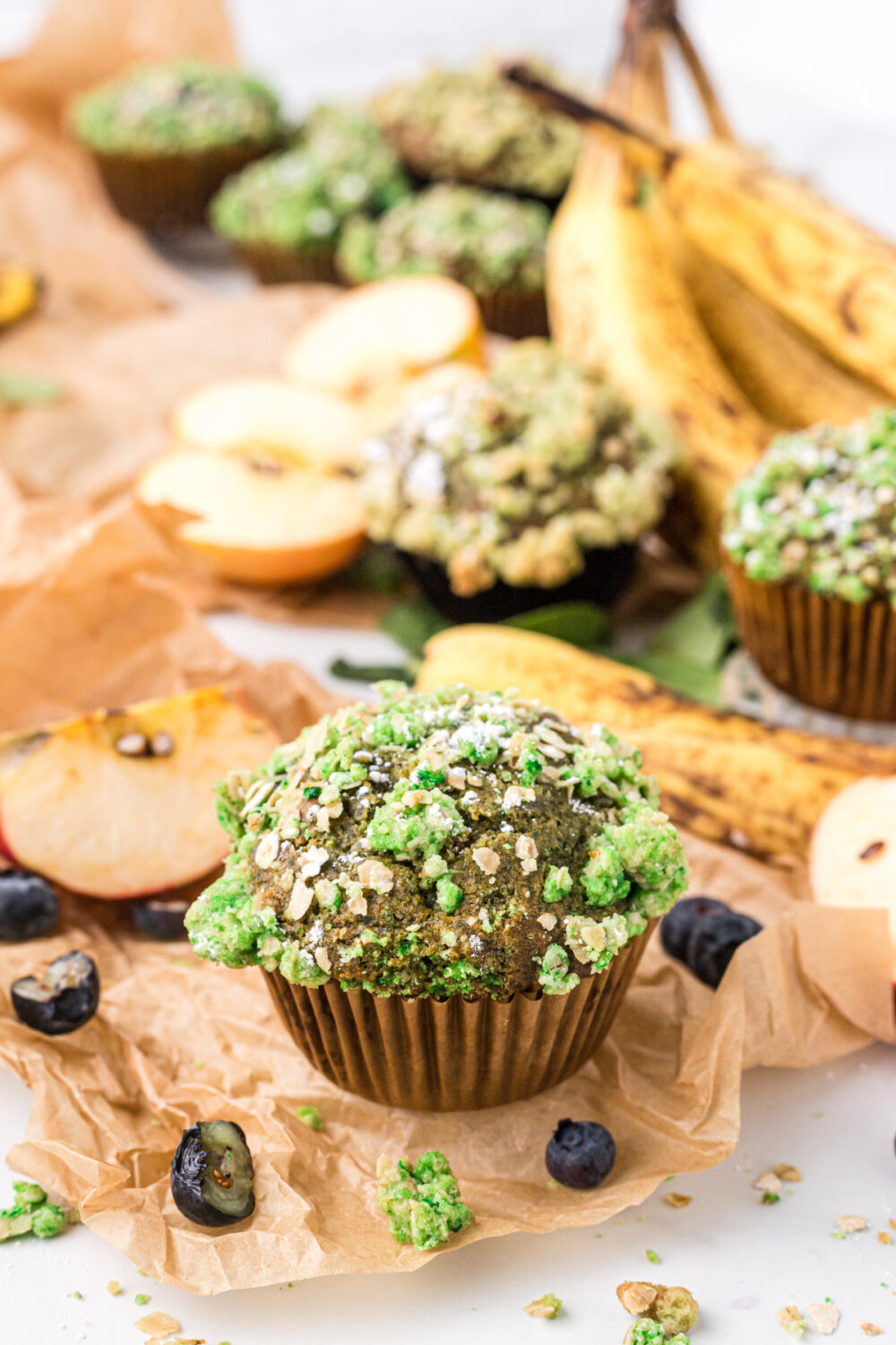 Green muffins surrounded by bananas and blueberries.