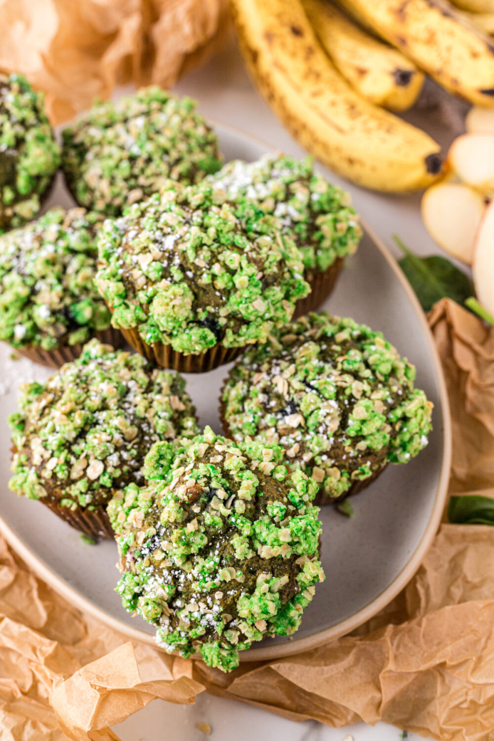 Green muffins stacked on a tray next to bananas.