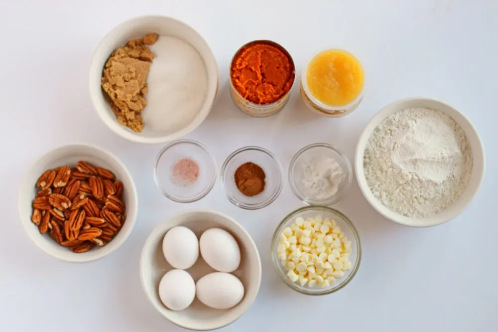 Pumpkin, eggs, pecans, and other ingredients to make snack cakes in bowls. 