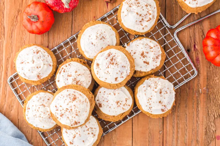 Iced pumpkin cookies on a wire rack.