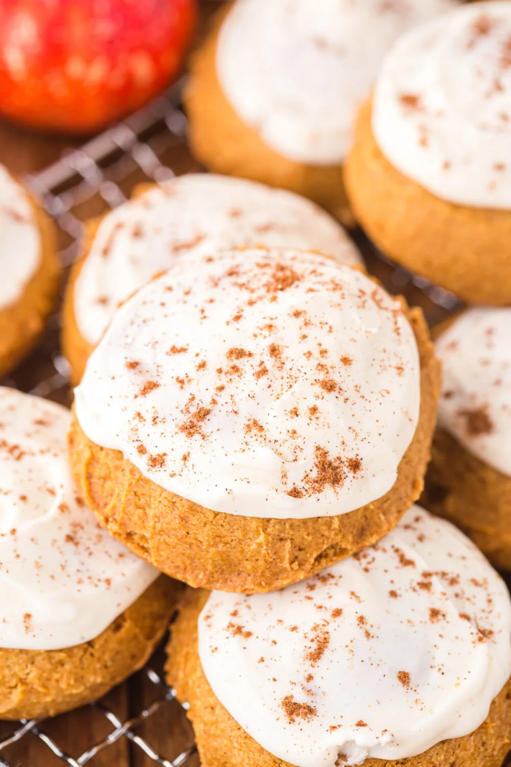 Pumpkin cookies with cream cheese frosting on a rack.