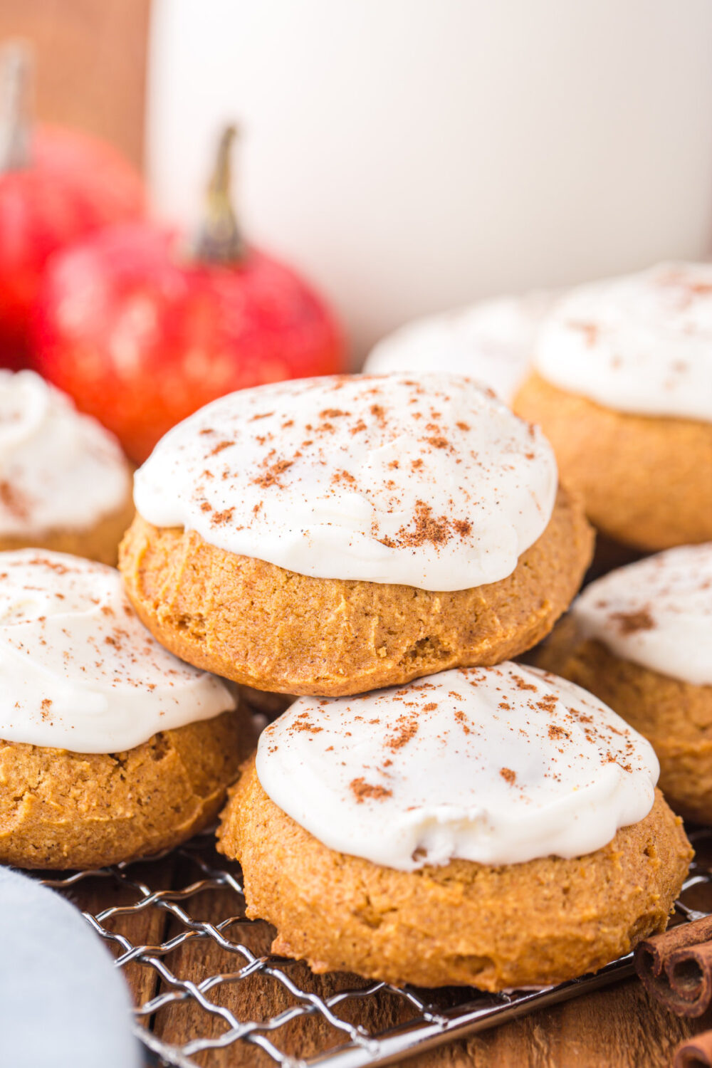 Pumpkin cookies with frosting on a rack.