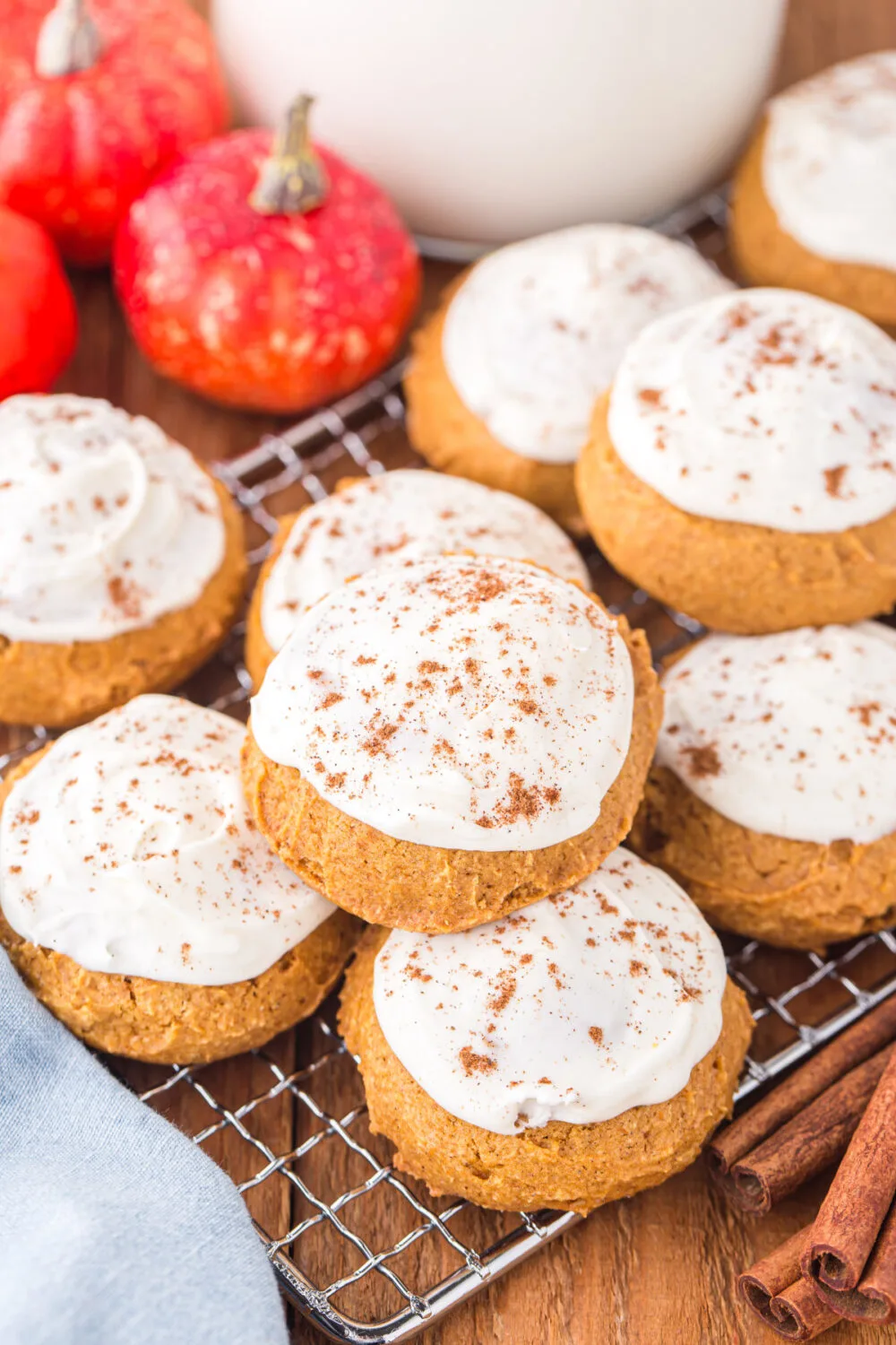 Pumpkin sugar cookies with cream cheese frosting on a rack. 