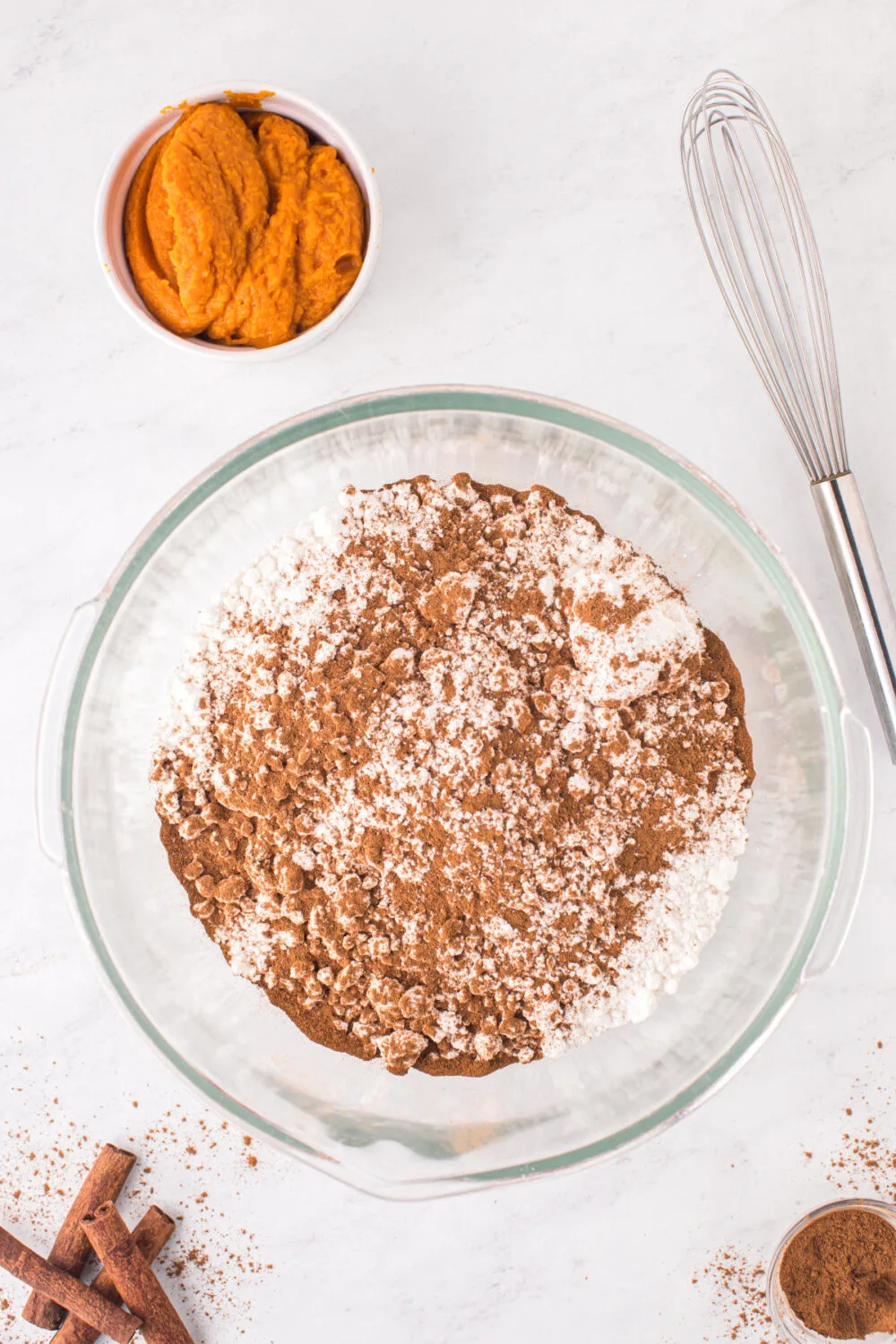 Bowl of dry ingredients next to pumpkin puree.