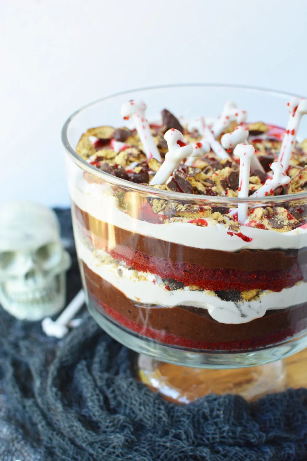 Vampire trifle topped with bones and next to Halloween decor on a table. 