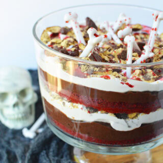 Vampire trifle topped with bones and next to Halloween decor on a table.