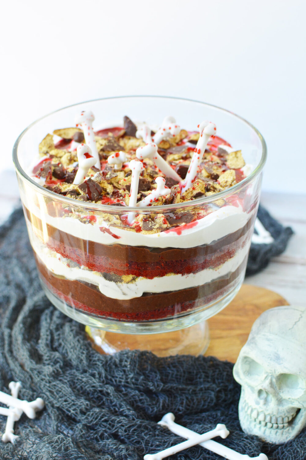 Layered red velvet trifle topped with bones for Halloween. 
