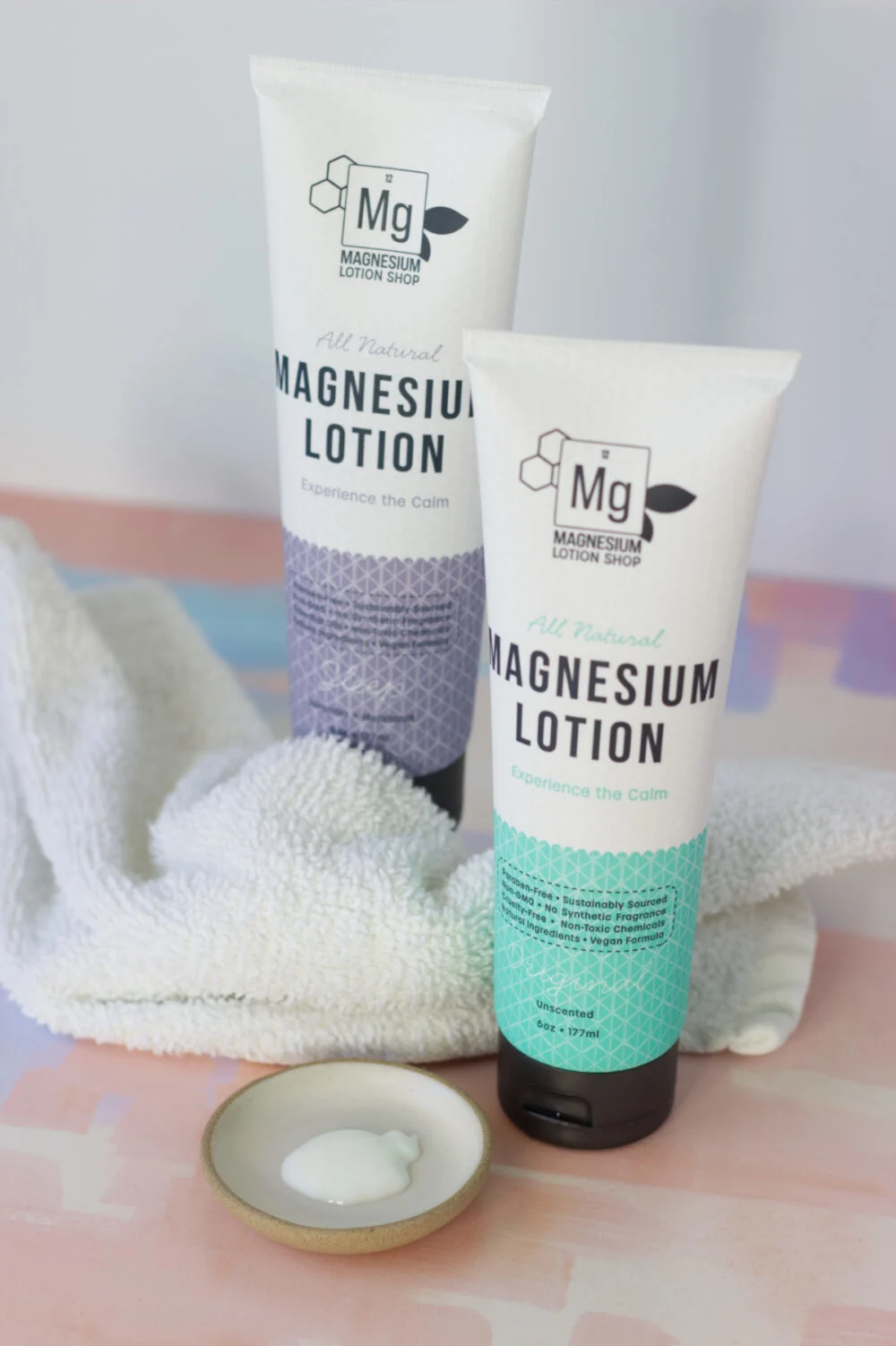 Two tubes of magnesium lotion next to a rag and a dish of the lotion.