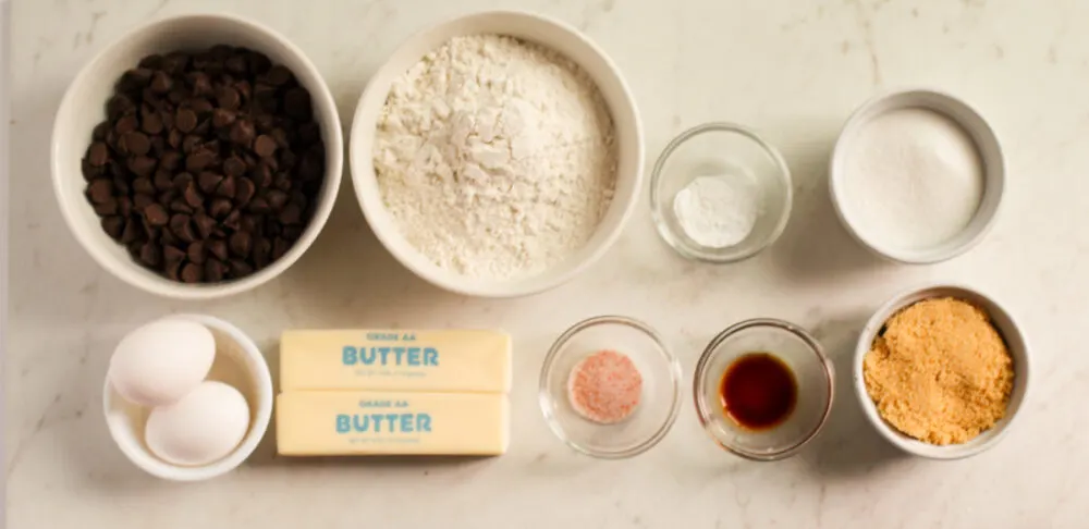 Flour, chocolate chips, eggs, butter, and other ingredients in bowls. 