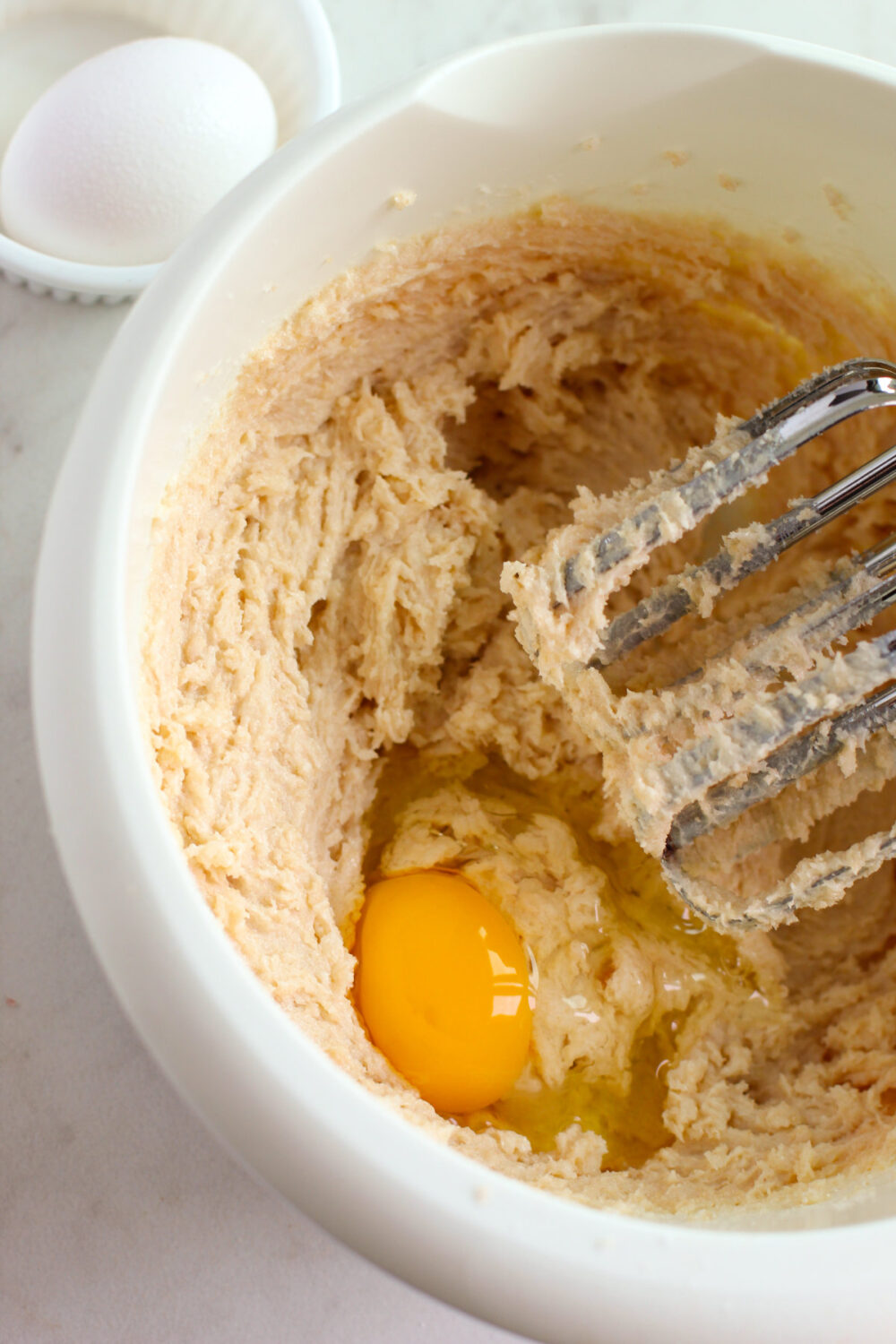 Egg in a mixing bowl with cookie dough batter. 