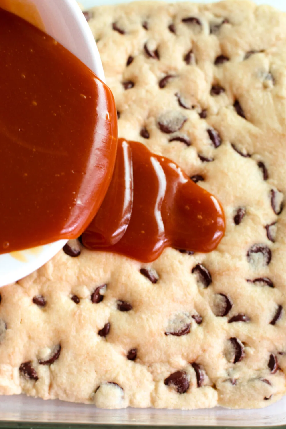 Pouring caramel sauce over a baked chocolate chip cookie. 