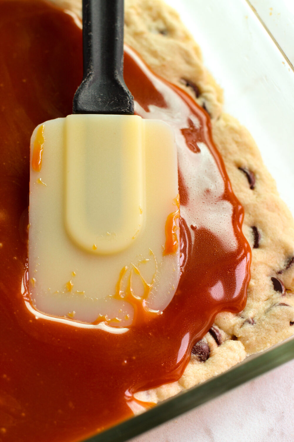 Using a spatula to smooth caramel over a cookie. 
