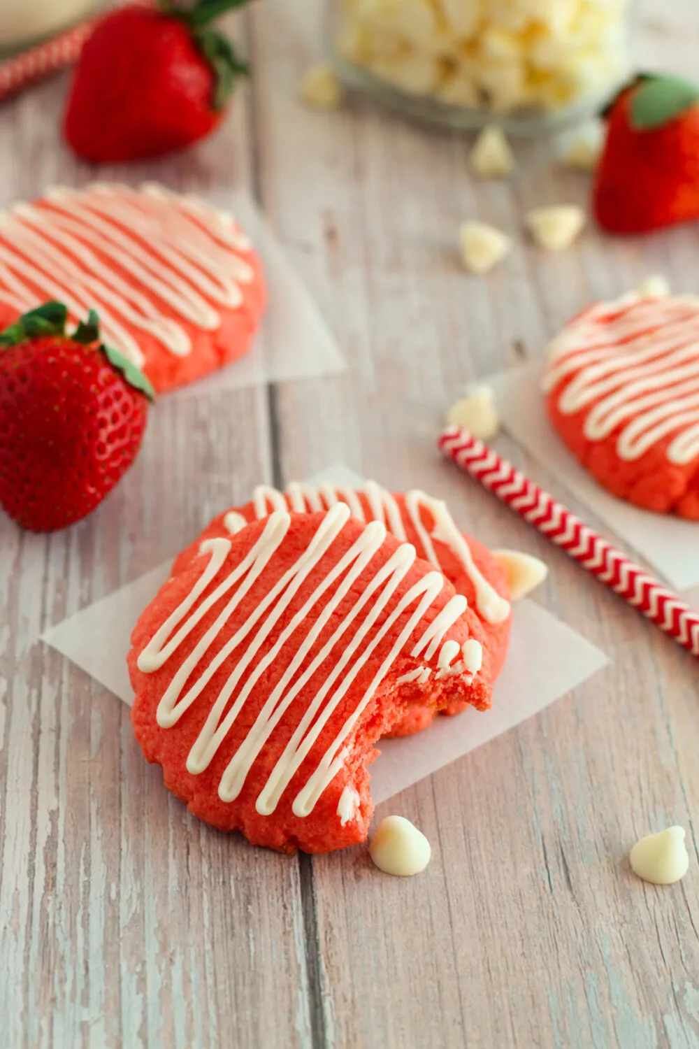 Strawberry cookies on a table with white chocolate chips and strawberries. 