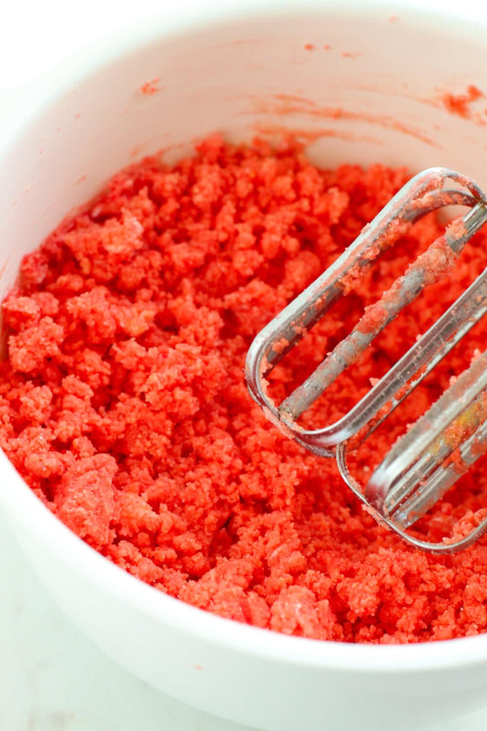 Strawberry cookie dough in a bowl with a mixer. 