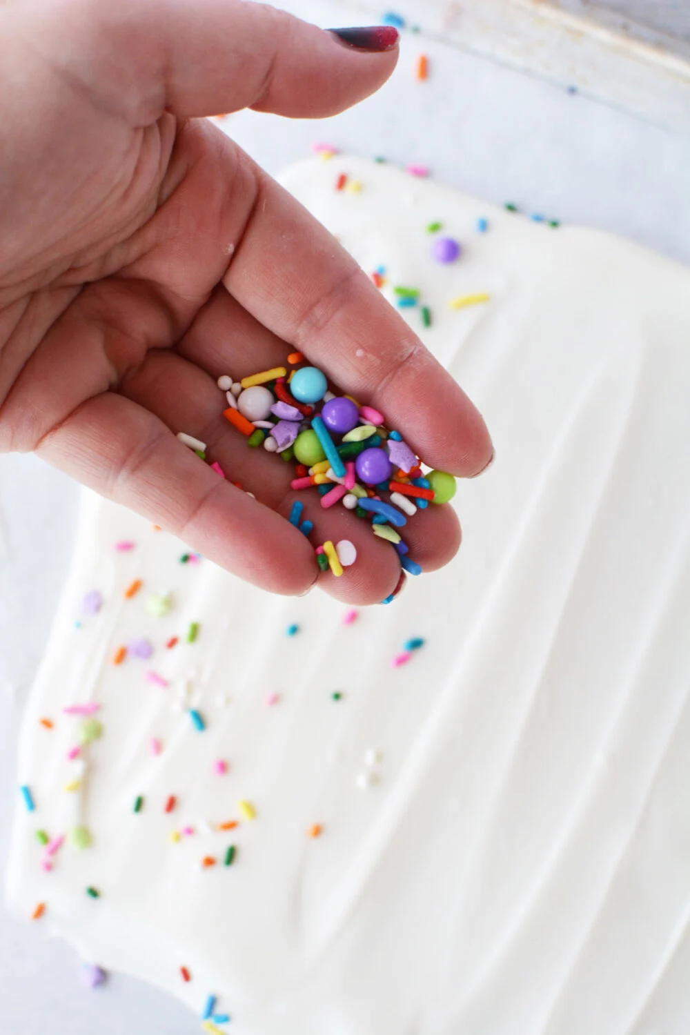 Sprinkling sprinkles onto melted almond bark. 