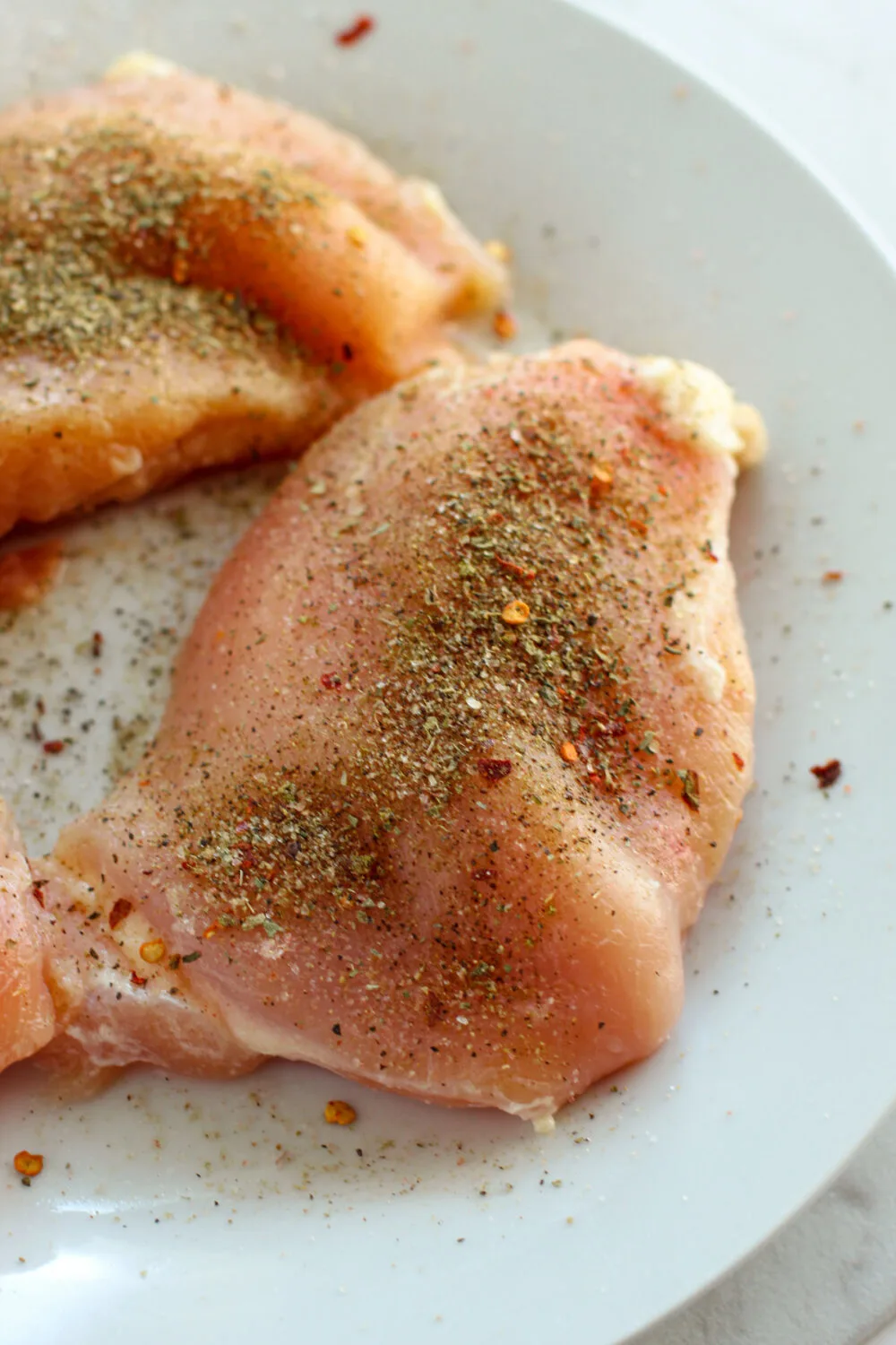 Seasoning on raw chicken breasts. 