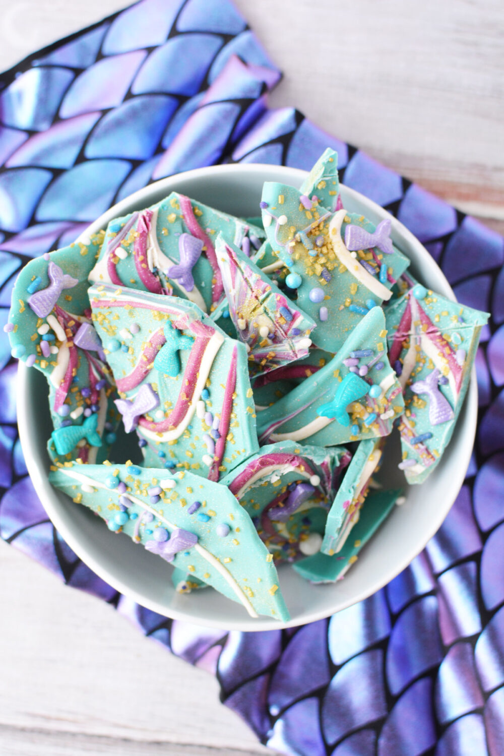 Bowl of mermaid bark candy on top of scale fabric. 