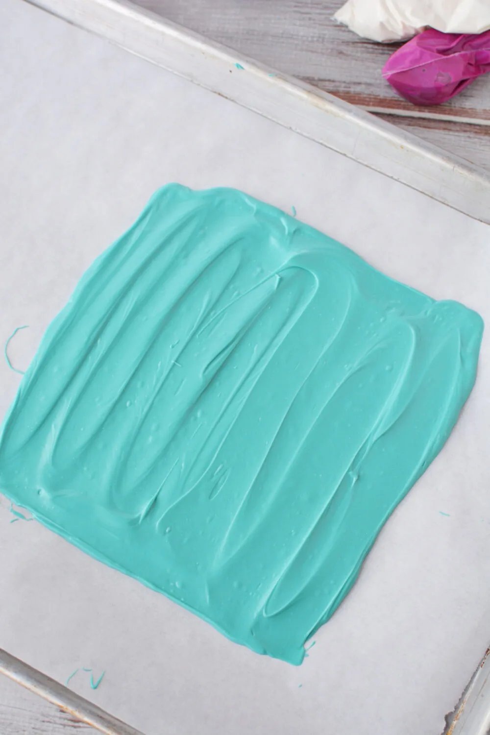 Melted turquoise candy melts on a baking sheet. 