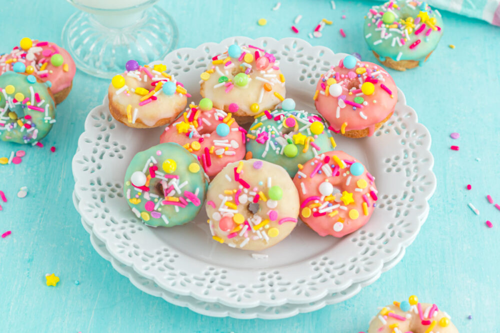 A plate of colorfully glazed mini donuts with sprinkles. 