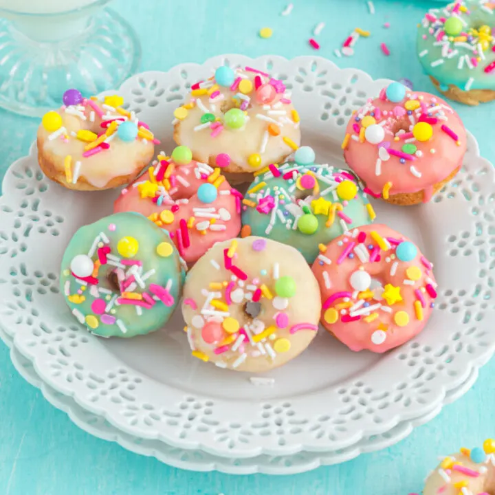 A plate of colorfully glazed mini donuts with sprinkles.
