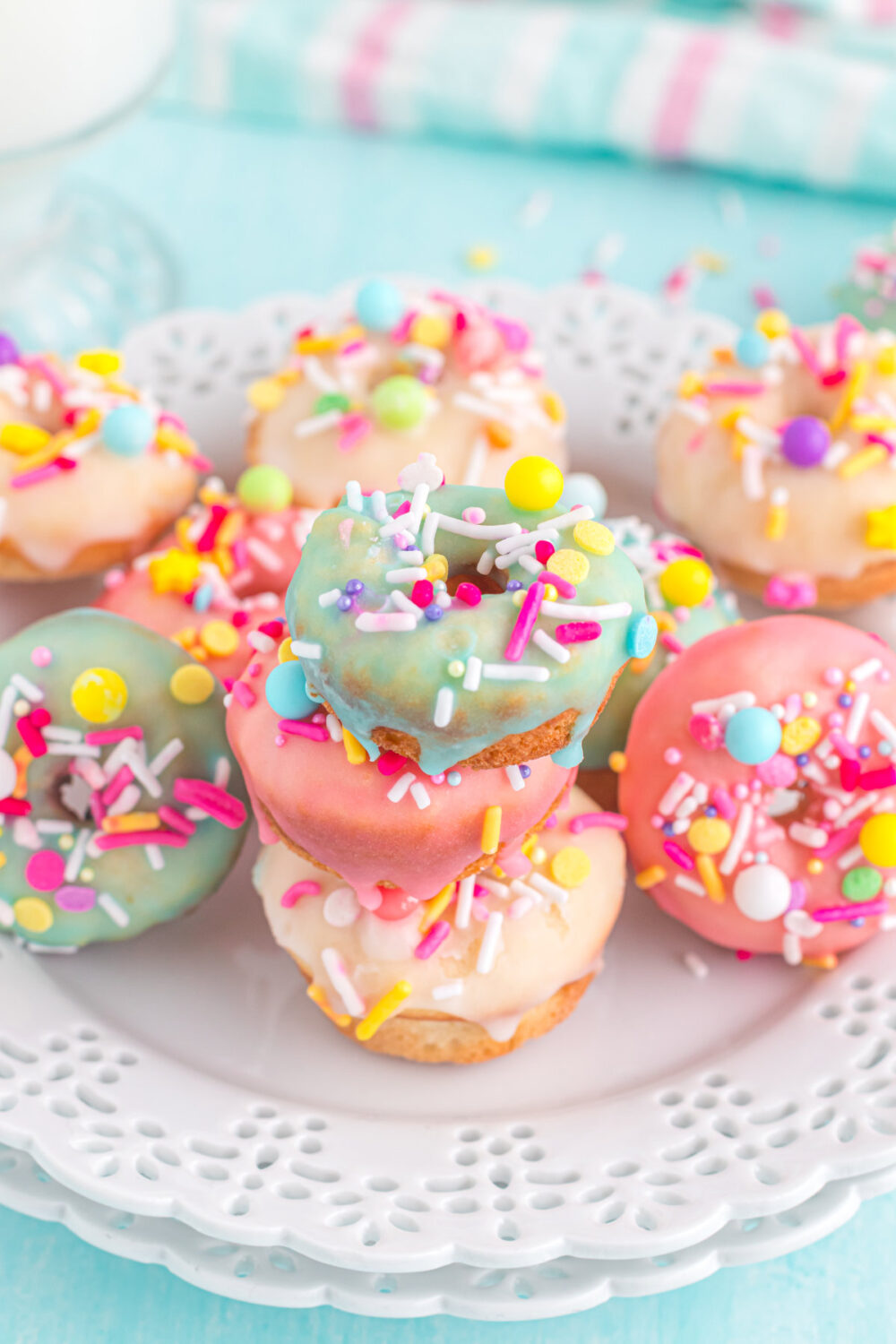 Plate full of tiny donuts with blue, yellow, and pink glaze and sprinkles. 
