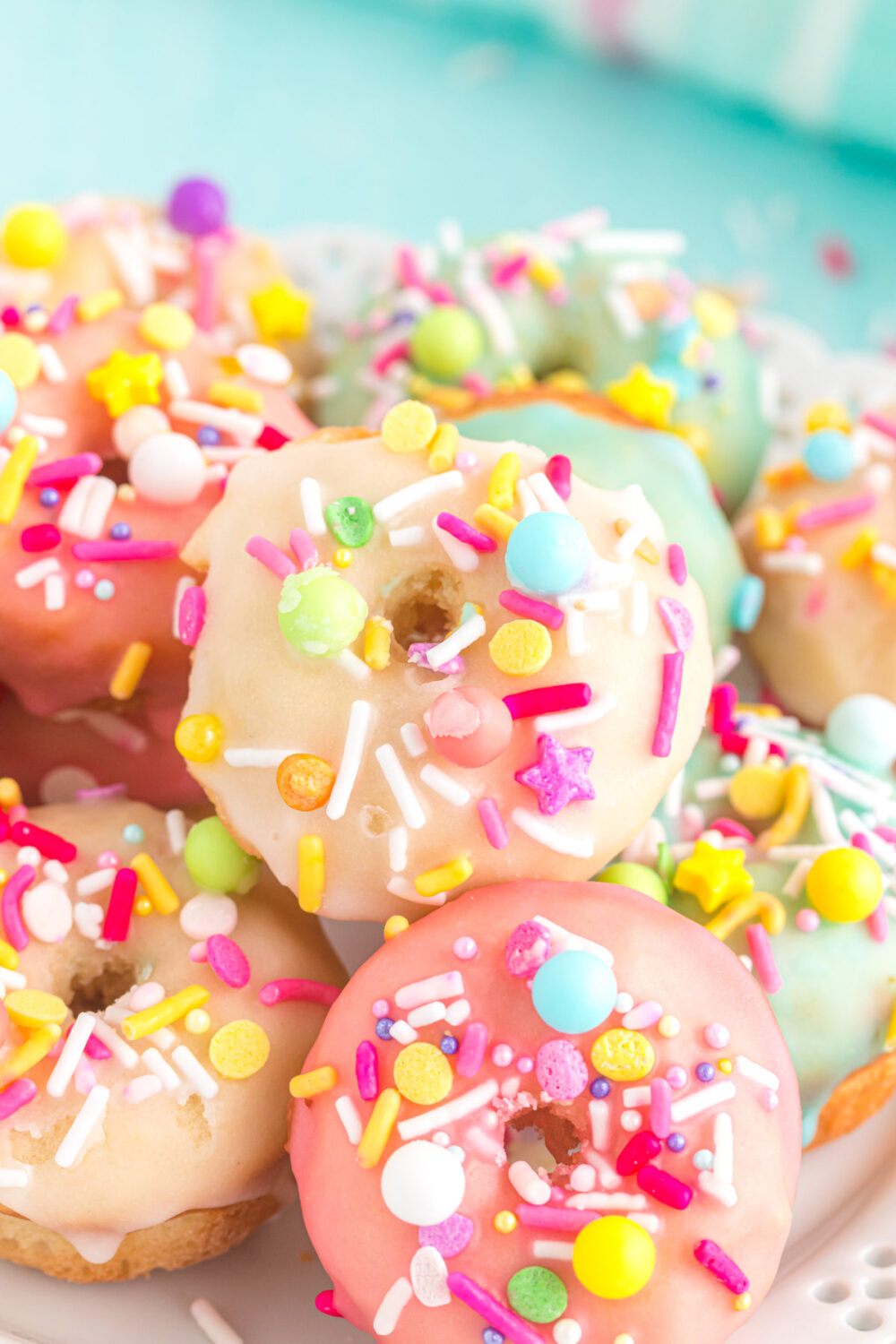 Pink, yellow, and blue mini donuts with sprinkles. 