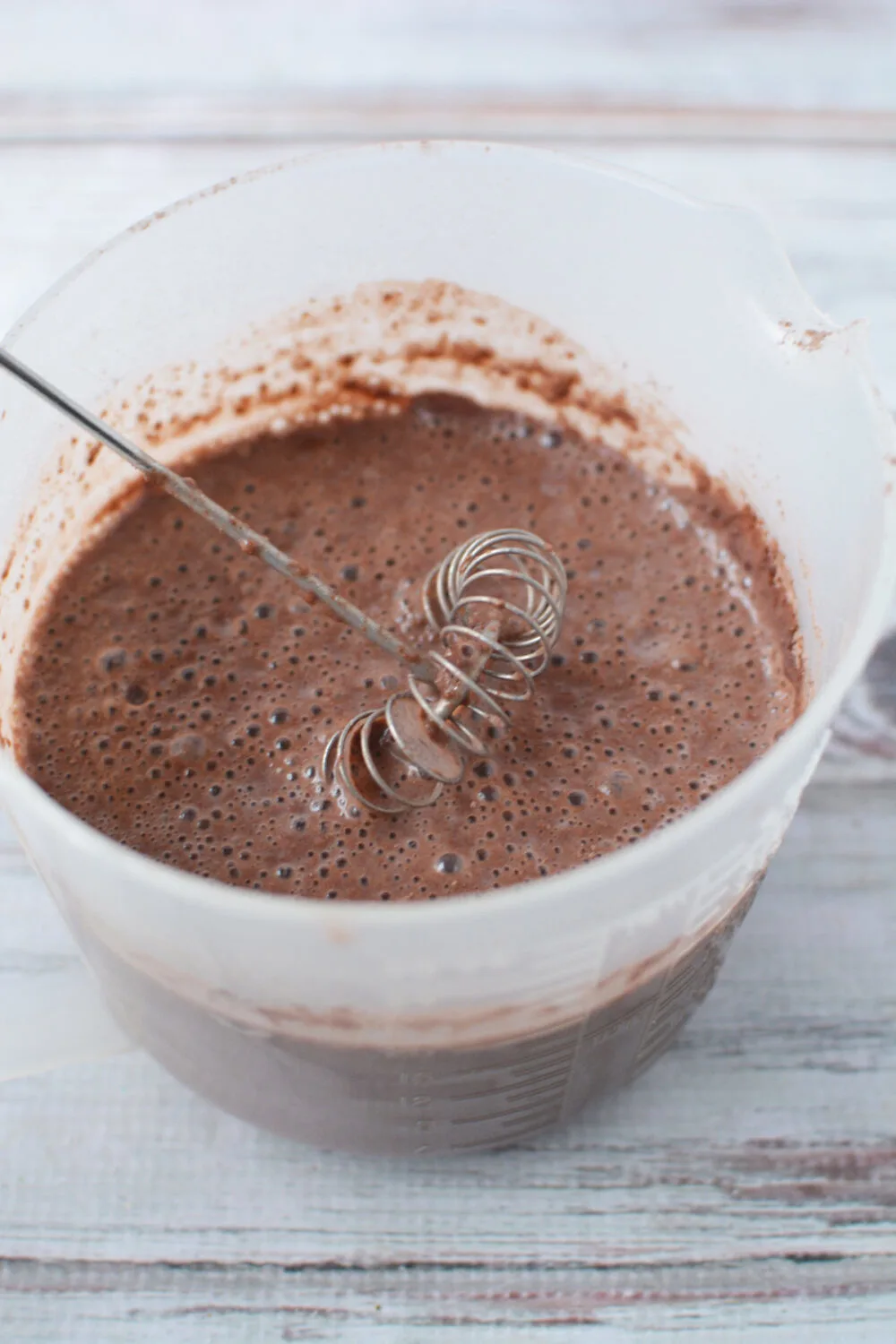 Mixing chocolate pudding in a container.