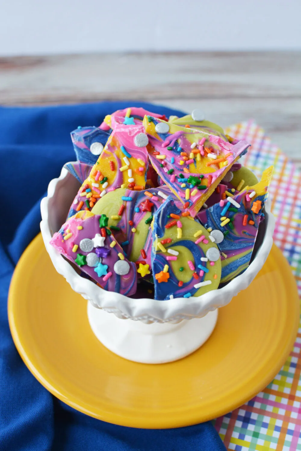 White bowl full of rainbow candy bark with sprinkles. 