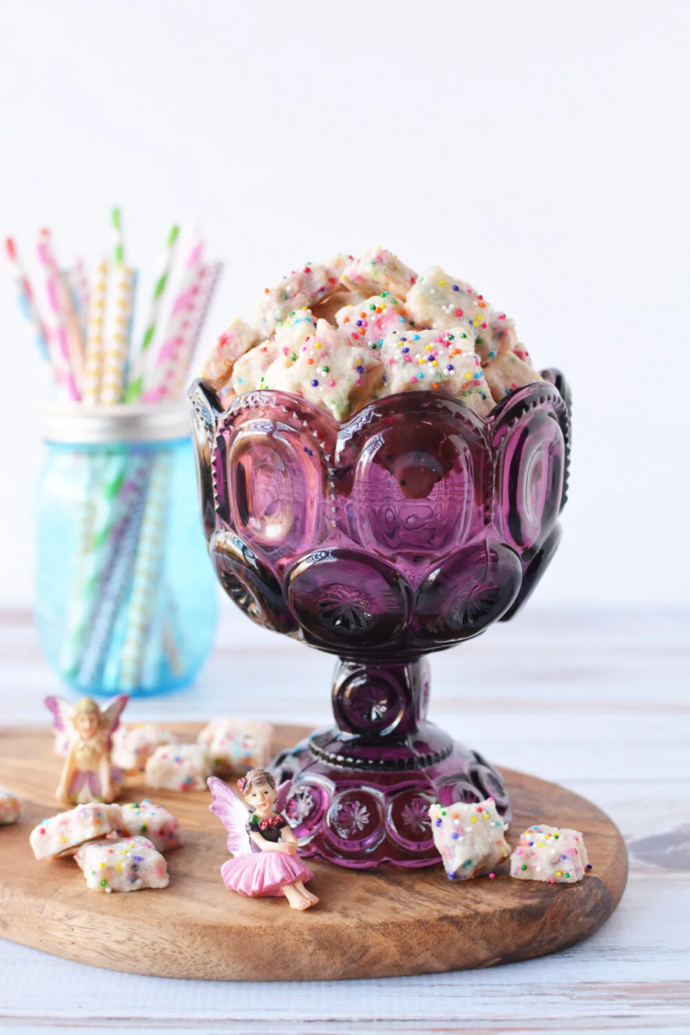 Purple mug filled with fairy shortbread cookies with rainbow nonpareils. 