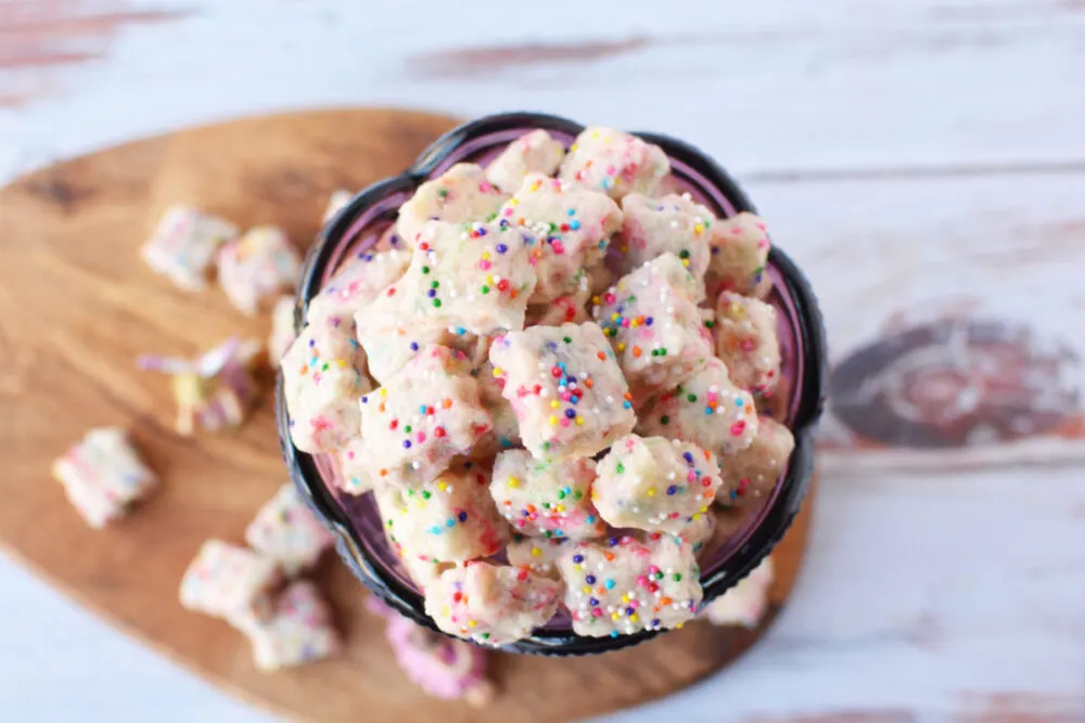 A purple chalice filled with tiny shortbread bites with rainbow sprinkles. 