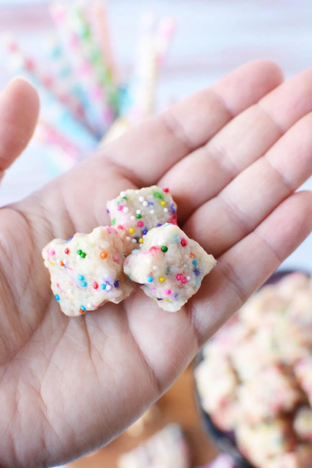 Holding fairy shortbread bites with rainbow sprinkles. 