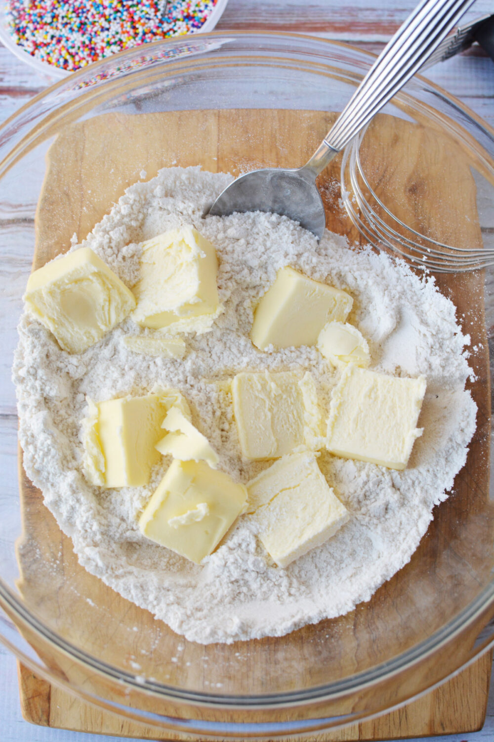 Chunks of butter in a bowl with flour and sugar. 
