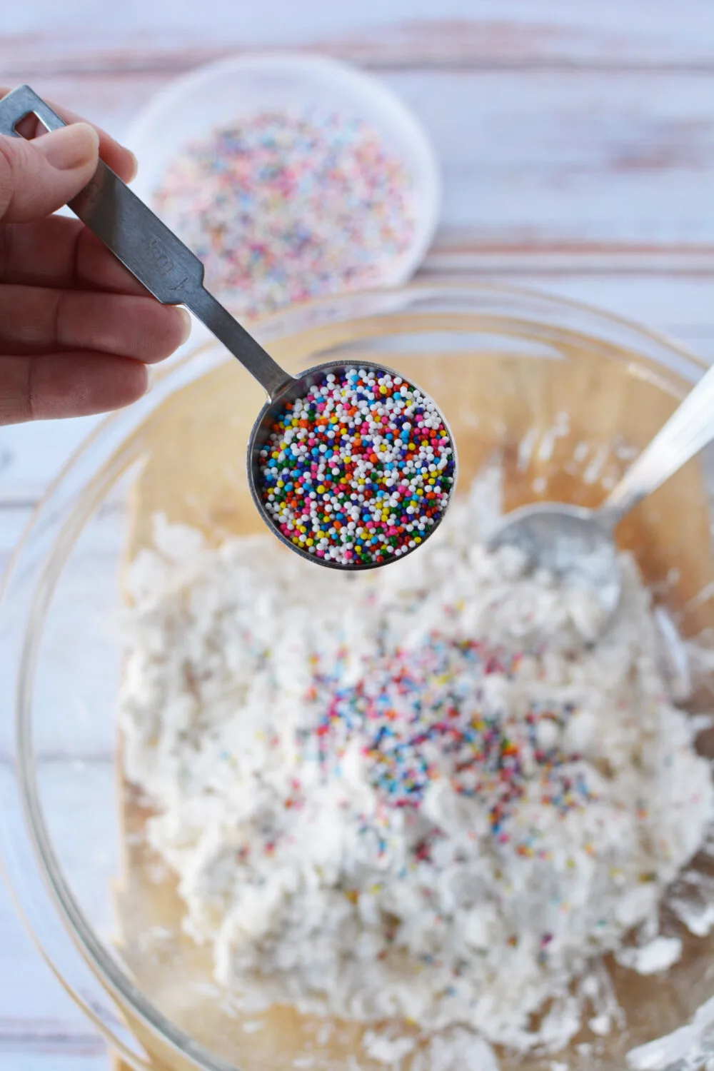 Adding rainbow nonpareils to cookie dough. 