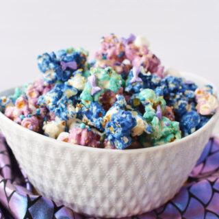 Bowl of mermaid popcorn on top of mermaid fin purple fabric.