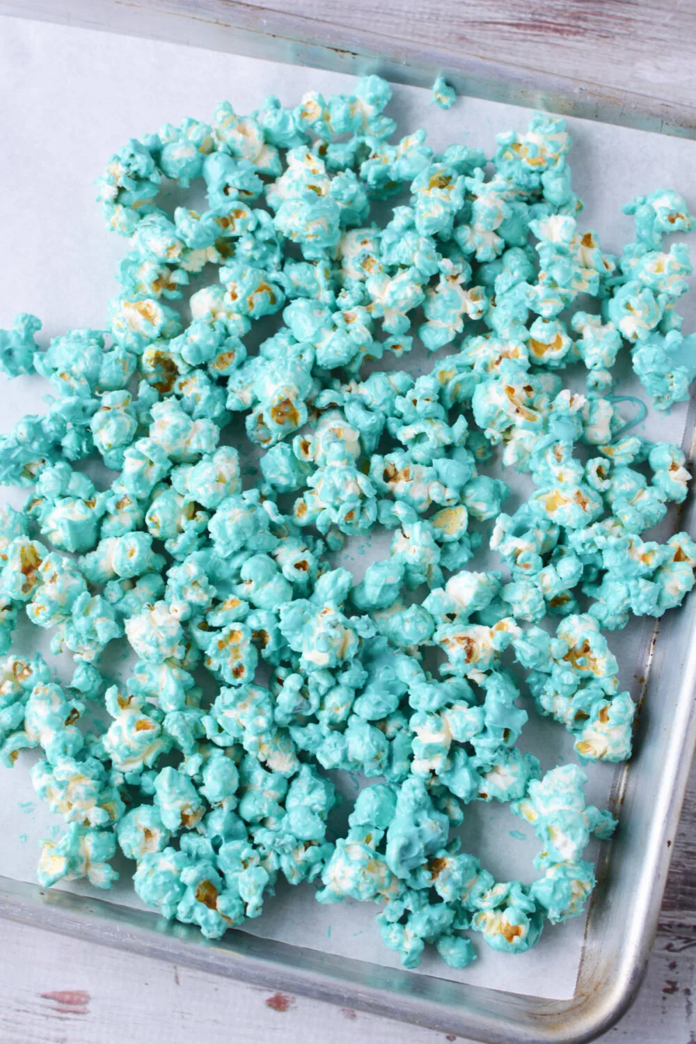 Candy coated blue popcorn on a baking sheet.