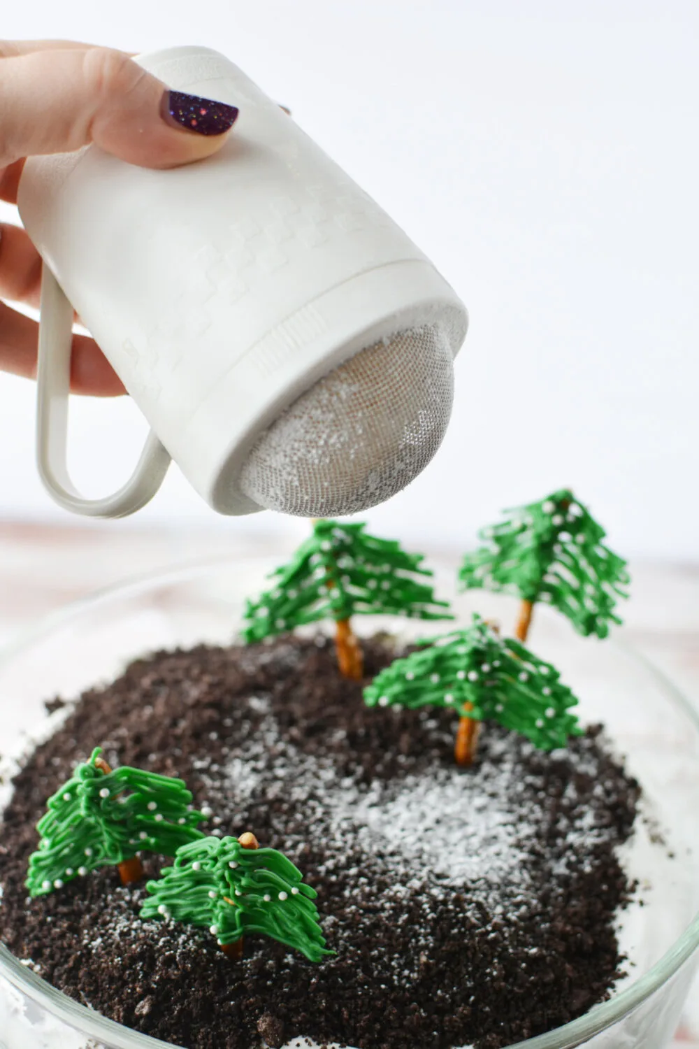 Sprinkling powdered sugar on top of a winter wonderland trifle. 