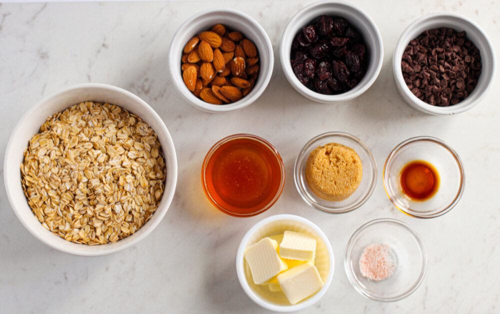 Oats, almonds, honey, and other ingredients in bowls. 