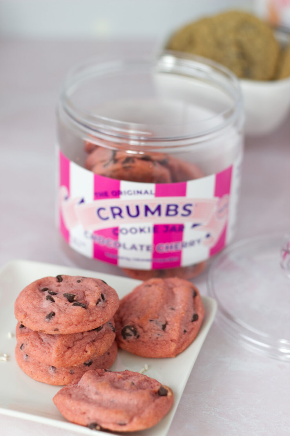 Cherry chip cookies from Crumbs Bakeshop on a plate and in their cookie jar. 