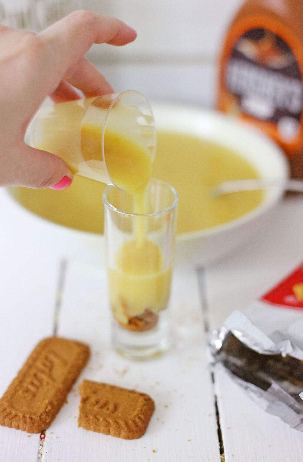 Pouring pudding over cookies in a shot glass. 