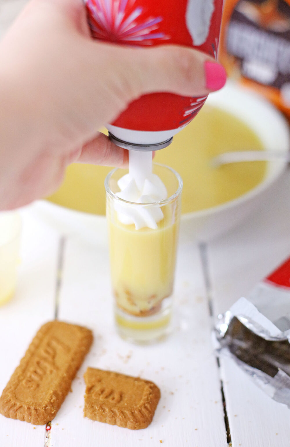 Adding whipped cream to pudding shots. 