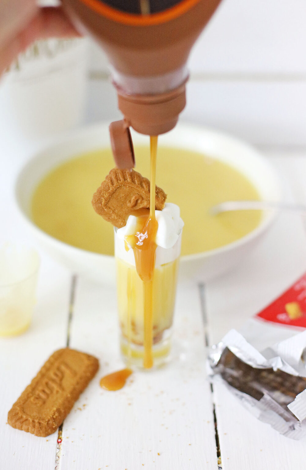 Drizzling caramel syrup on top of a pudding shot. 