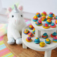 Mini unicorn poop cookies on a display next to a stuffed animal.