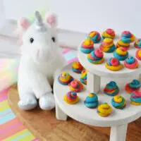 Mini unicorn poop cookies on a display next to a stuffed animal.
