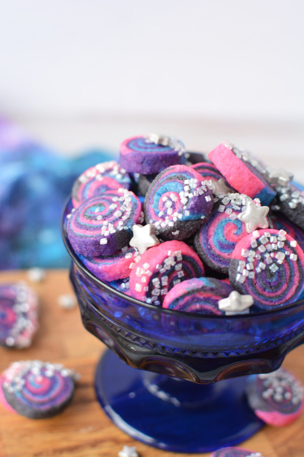 Blue cup filled with mini space cookies with silver sprinkles. 