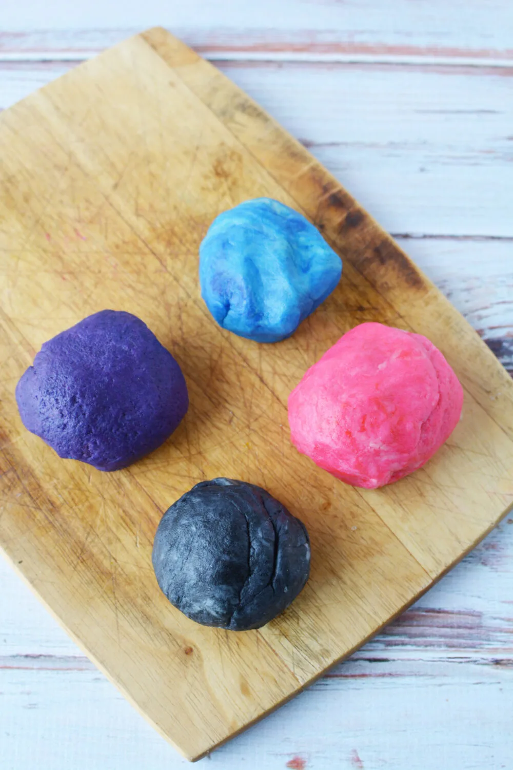 Four round balls of colored shortbread dough. 