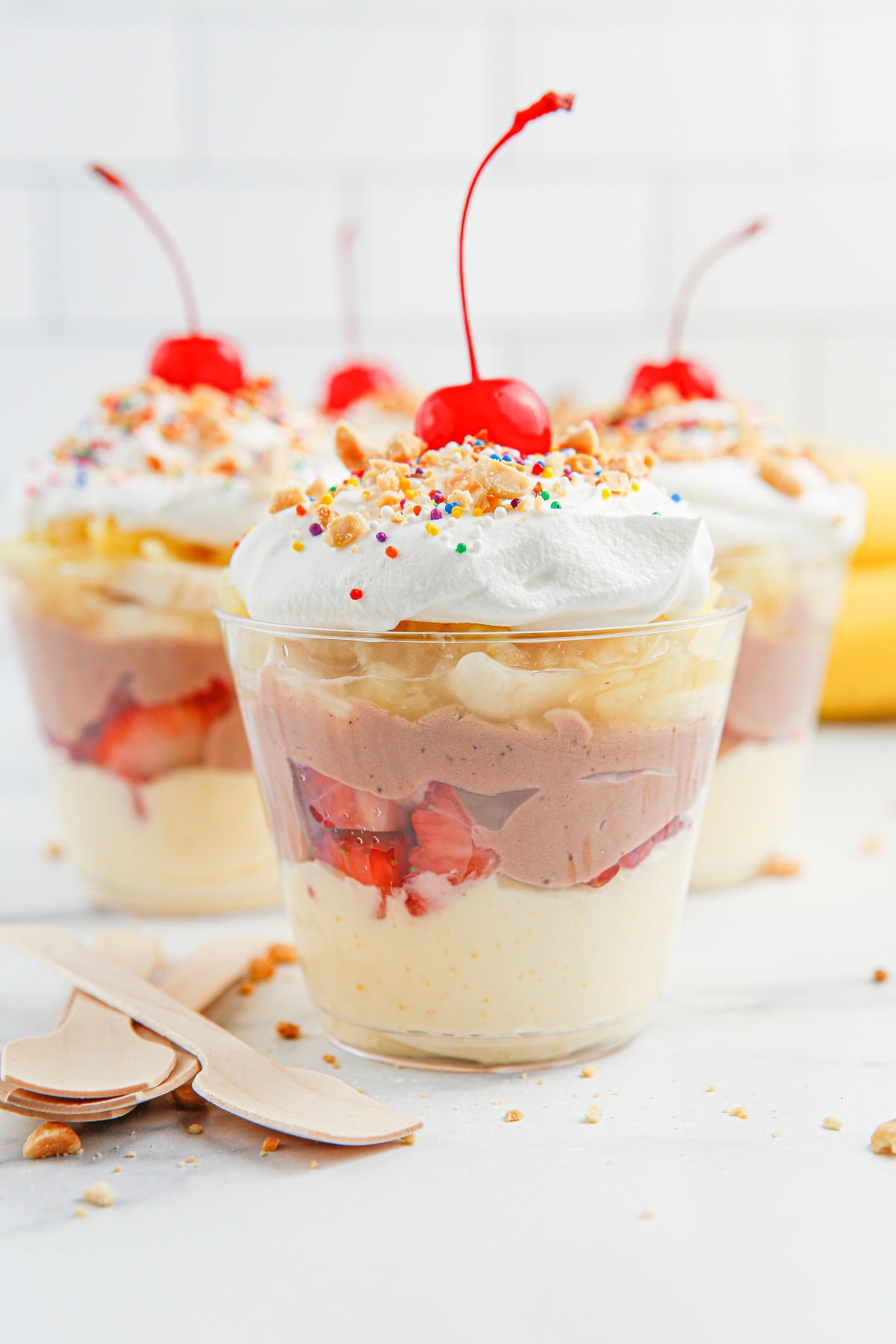 Layered banana split parfaits in cups.